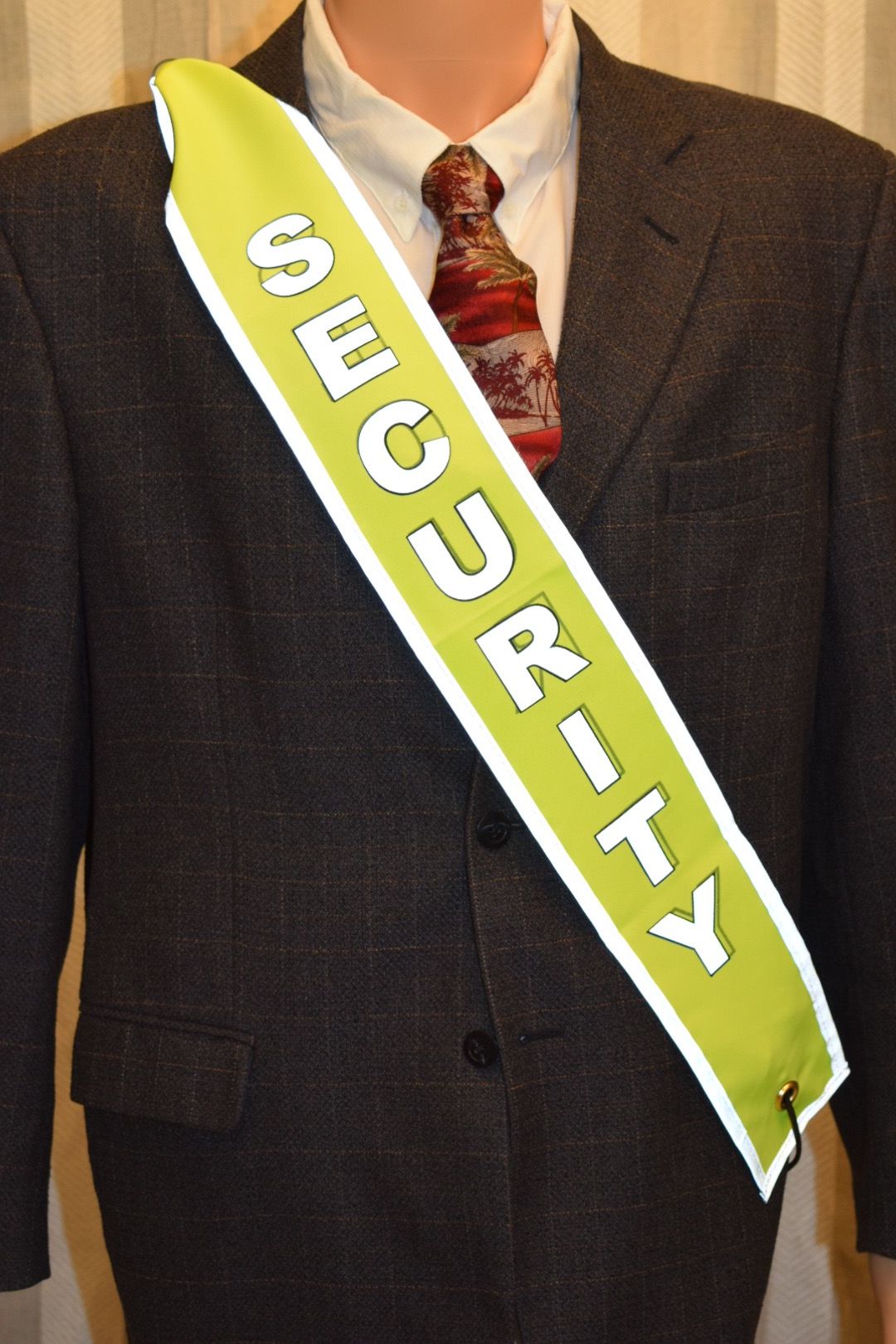 A hi-vis SECURITY banner with white reflective lettering, worn over a suit jacket